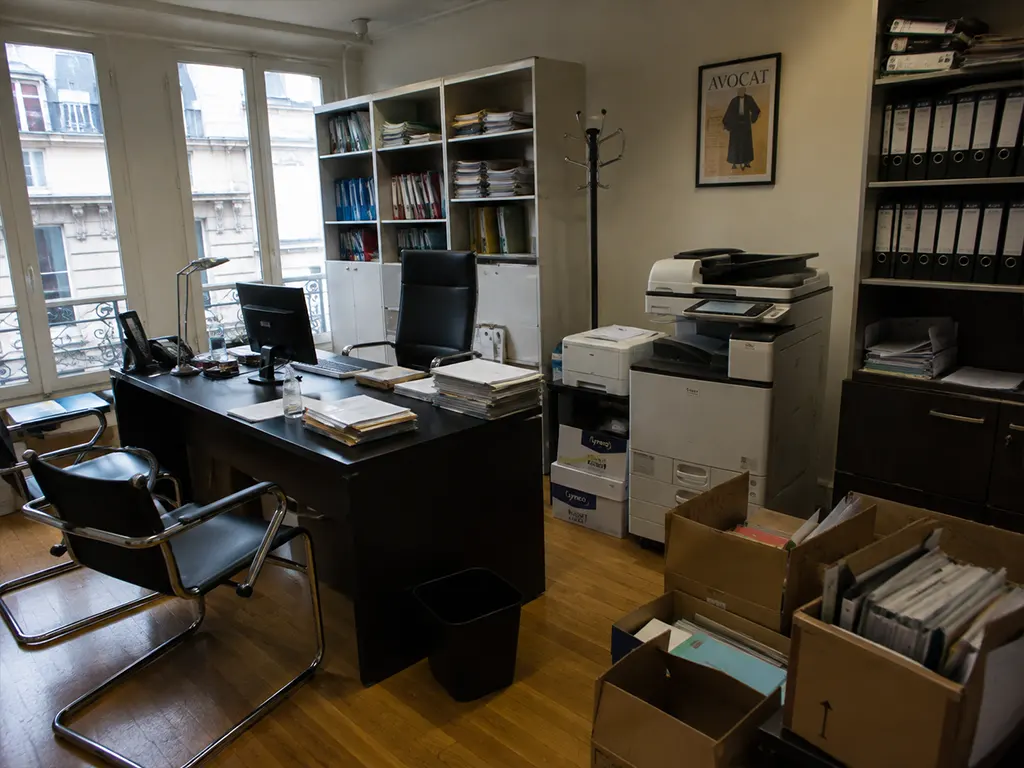 Bureau avec documents et équipements variés à débarrasser.